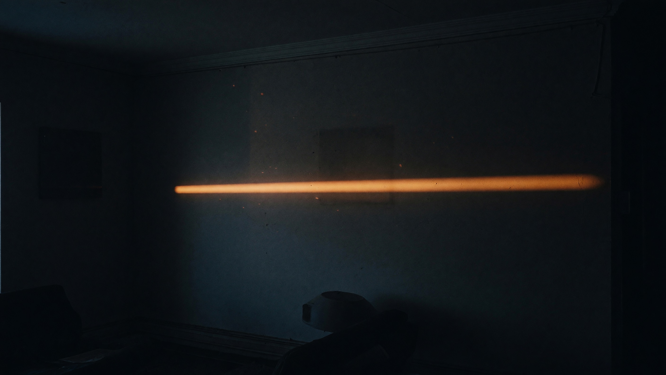 The same dark room after the light has thinned to a warm line