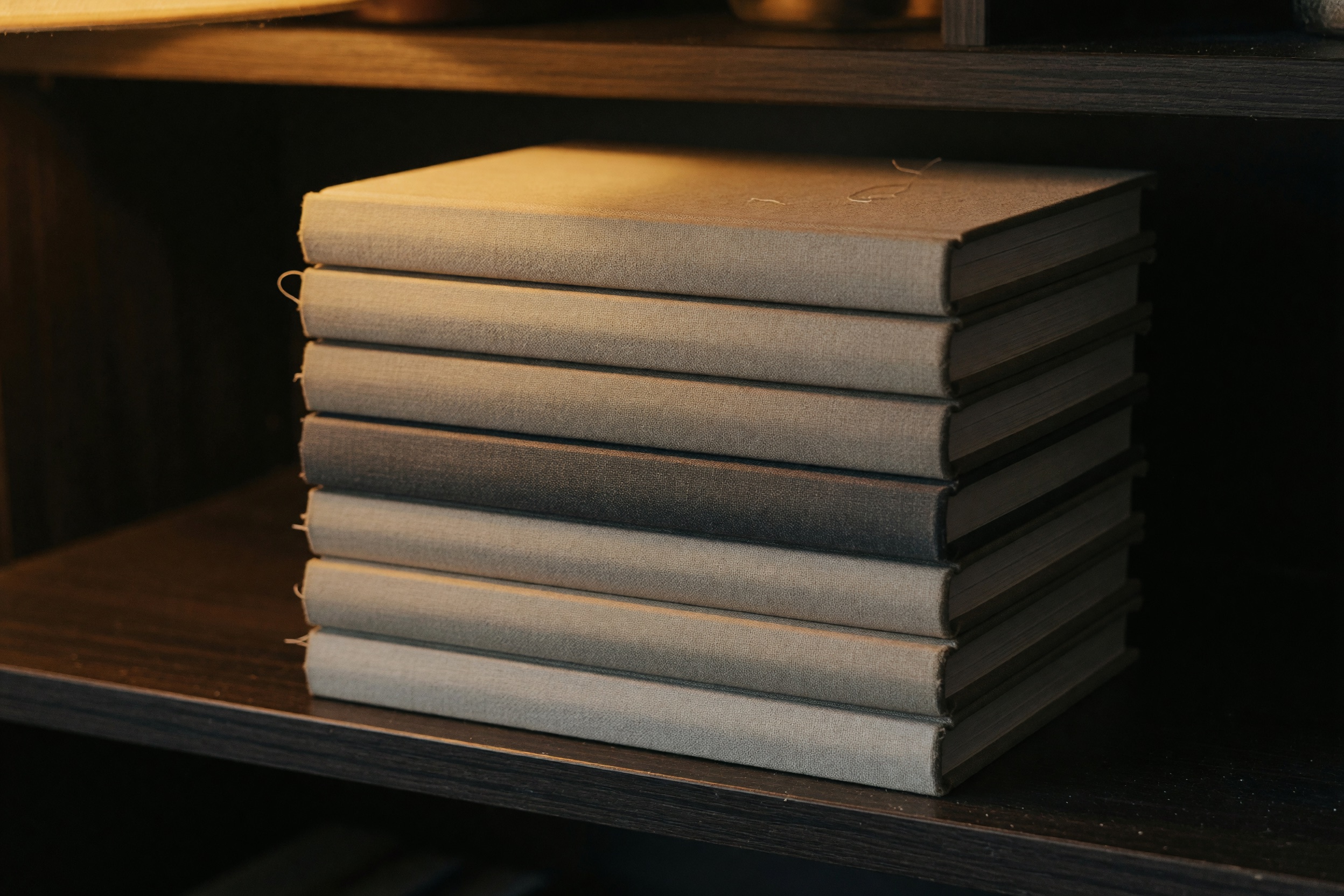A stack of plain unmarked books in warm lamplight