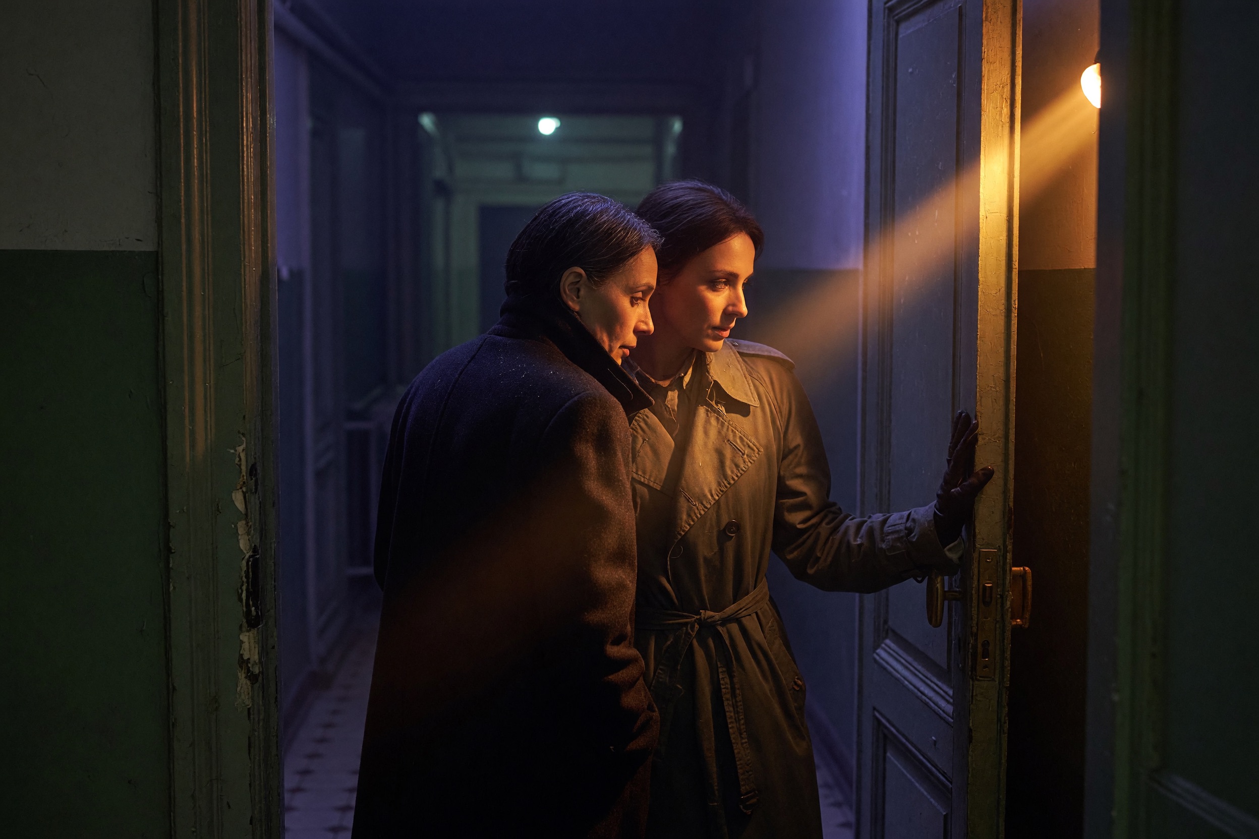 Two people paused in a dim doorway, faces turned from the light
